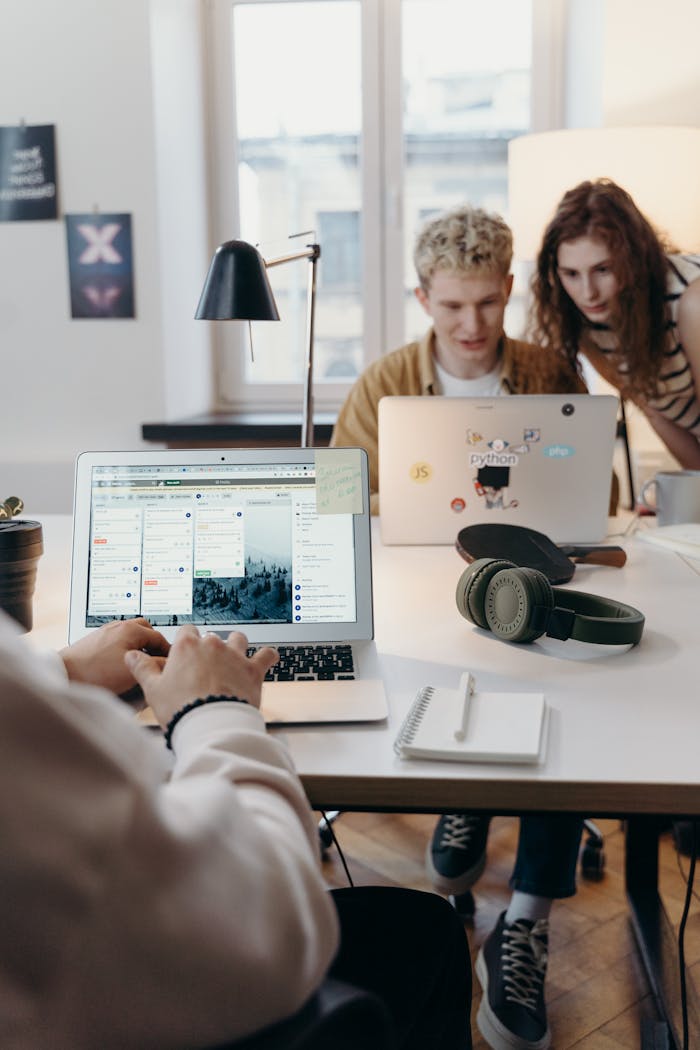 our-story Young team collaborating at a modern workspace with laptops and headphones.